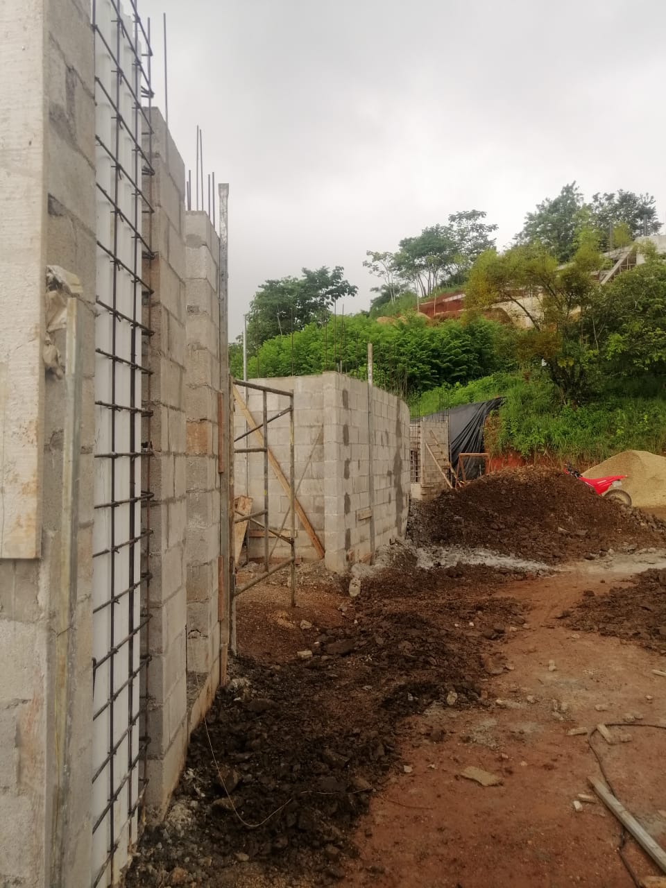 Se observa una obra de construcción en proceso con paredes de bloques y estructuras de acero expuestas.