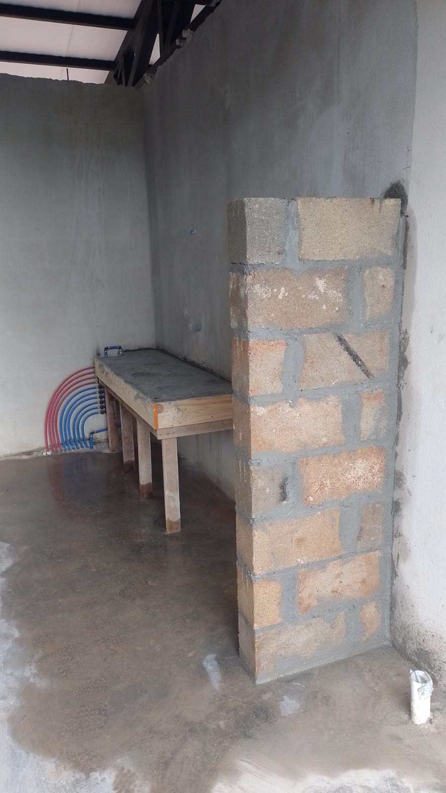 Se observa una estructura de bloques de concreto y una mesa de trabajo en construcción con tuberías expuestas.