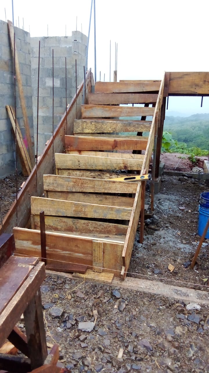 Se observa una estructura de madera en proceso de construcción para una escalera de concreto.