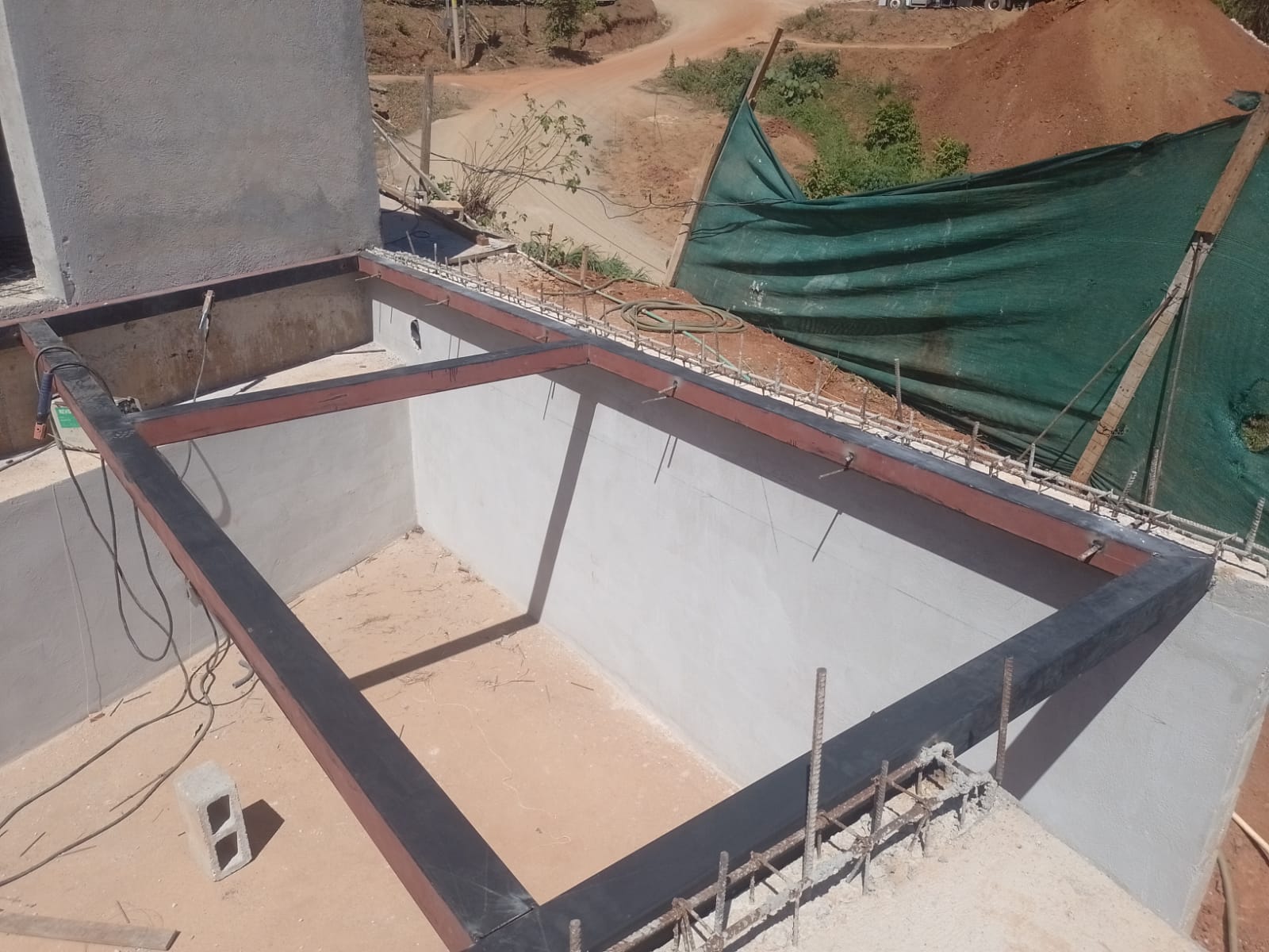 Se observa una estructura metálica rectangular instalada sobre una base de concreto en una obra de construcción.