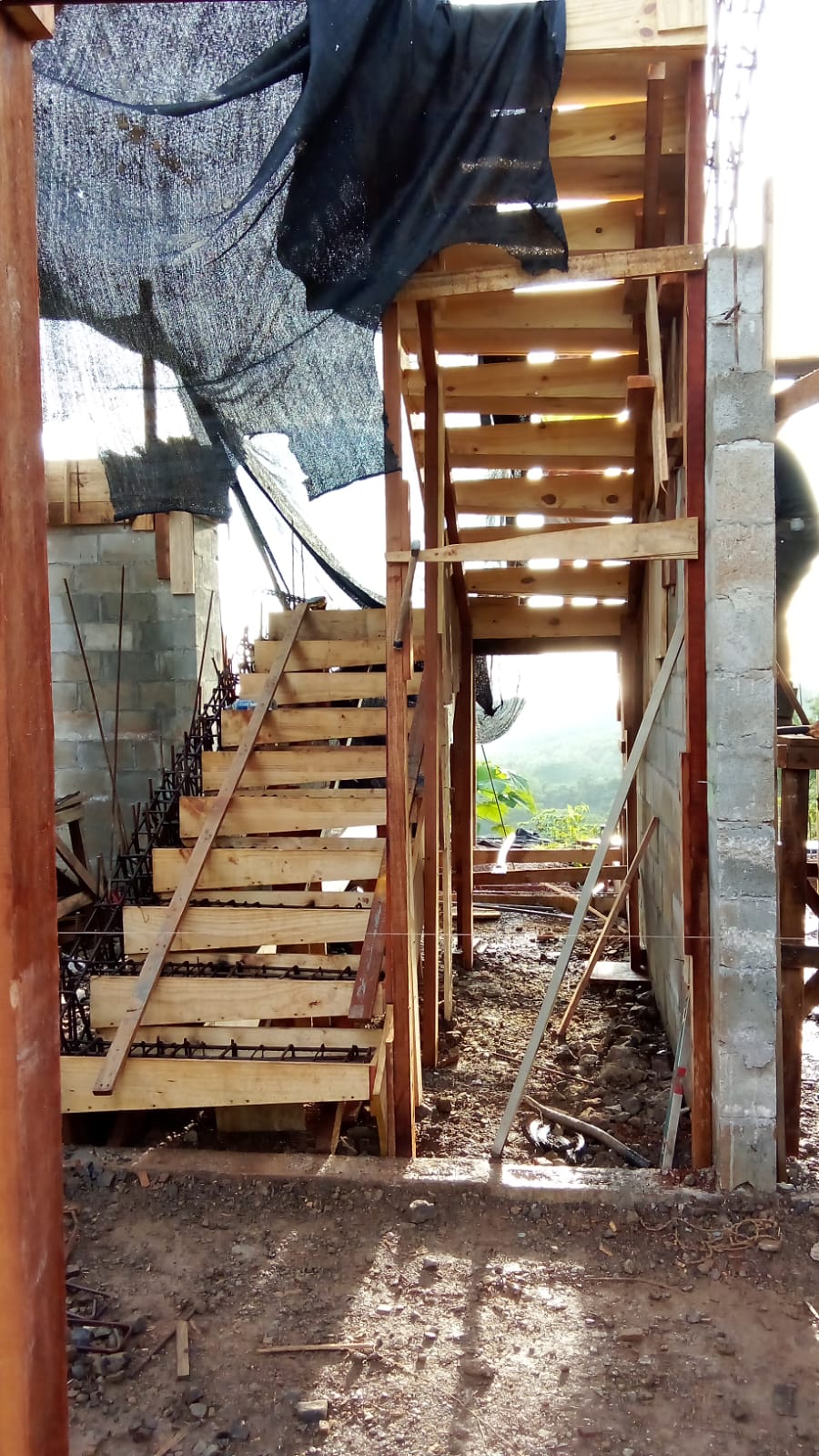 Se observa una estructura de escaleras de madera en proceso de construcción dentro de una obra civil.
