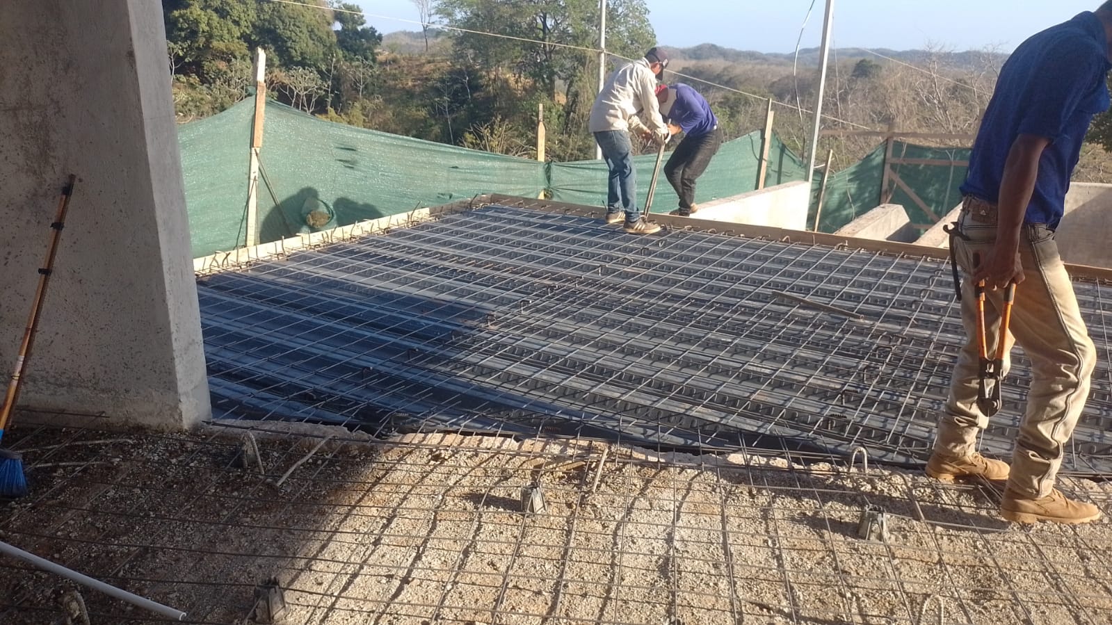 Trabajadores de construcción instalando una estructura de malla electrosoldada para un piso o losa.