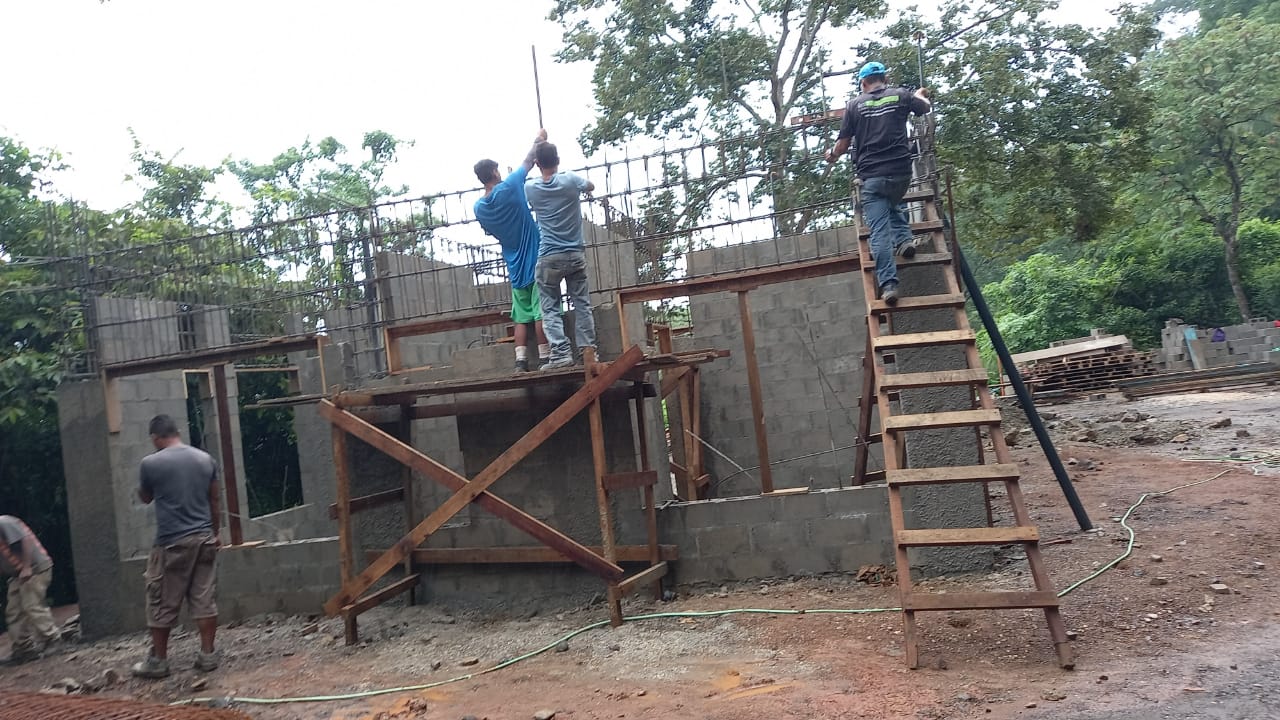 Un grupo de trabajadores realiza labores de construcción en la estructura de una casa de bloques.