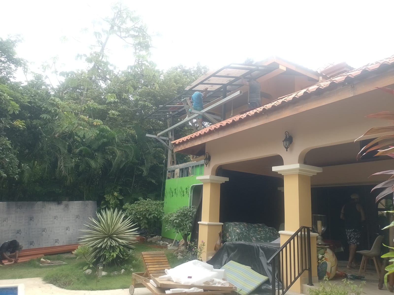 Dos trabajadores realizan labores de construcción en el techo de una casa residencial.