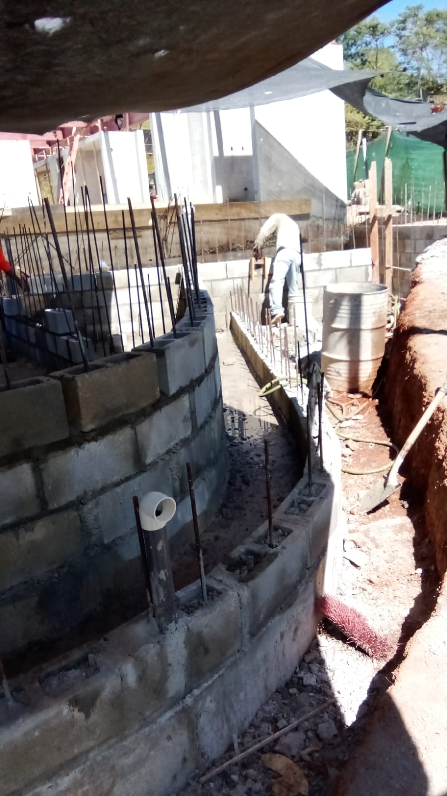 Un trabajador de la construcción levanta una pared curva de bloques de concreto en una obra.