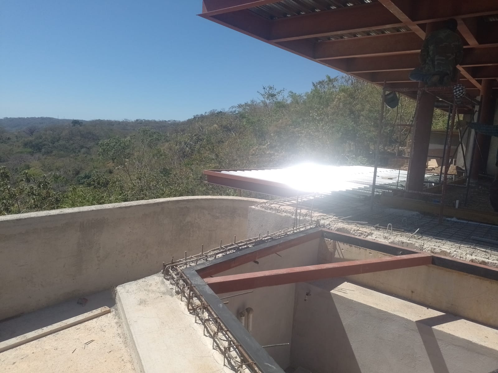 Se observa una estructura en construcción con vigas de acero y concreto en un entorno al aire libre.