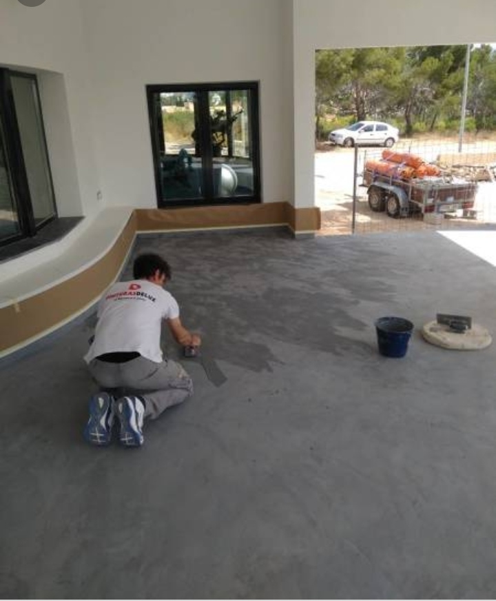 Un trabajador aplica un acabado de cemento pulido en el suelo de una terraza.