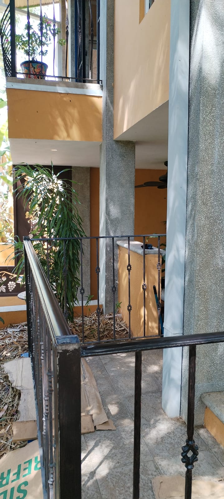 Vista de un balcón o terraza con barandales de hierro negro y paredes de color naranja.