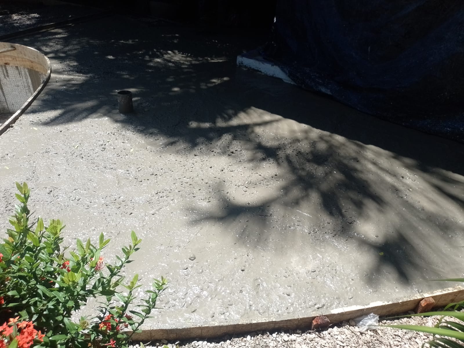 Se observa una superficie de concreto recién vertido en un área de construcción al aire libre.