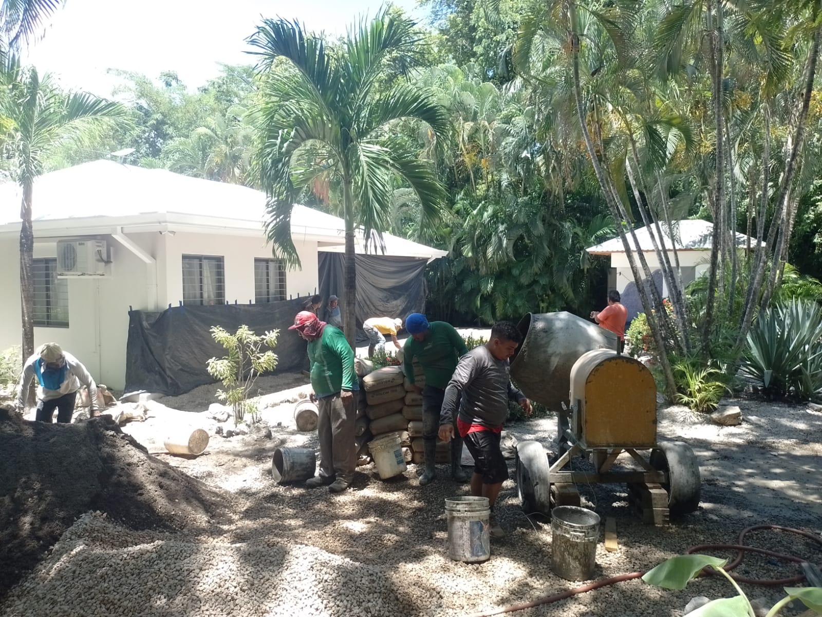 Un grupo de trabajadores realiza labores de construcción y mezcla de cemento en el exterior de una propiedad.