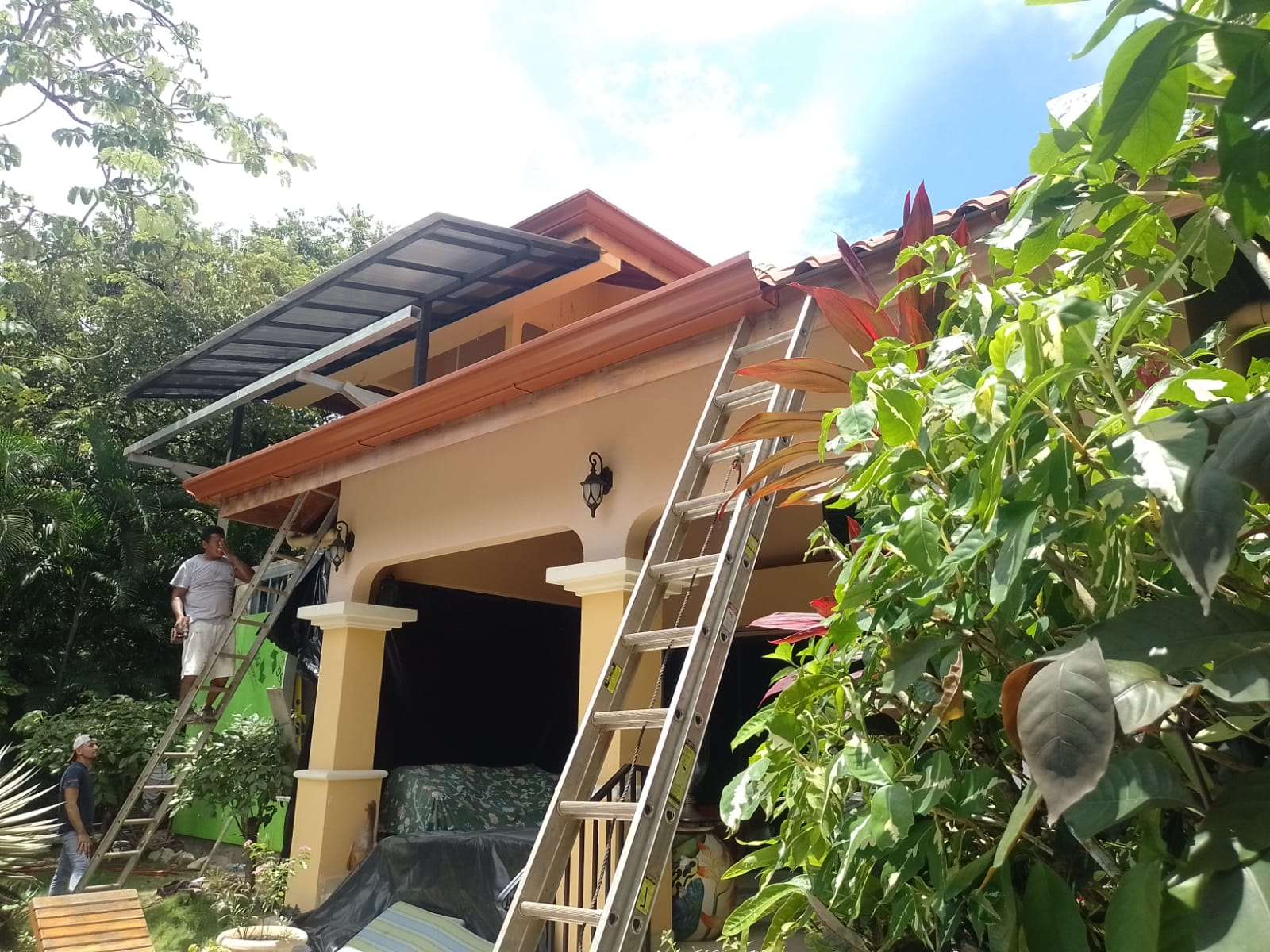 Un trabajador realiza labores de mantenimiento o construcción en el techo de una casa utilizando una escalera.