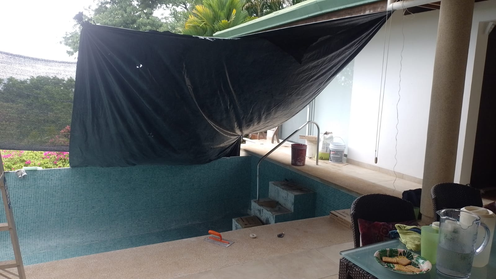 Se observa una piscina en proceso de mantenimiento o construcción cubierta con una lona negra.