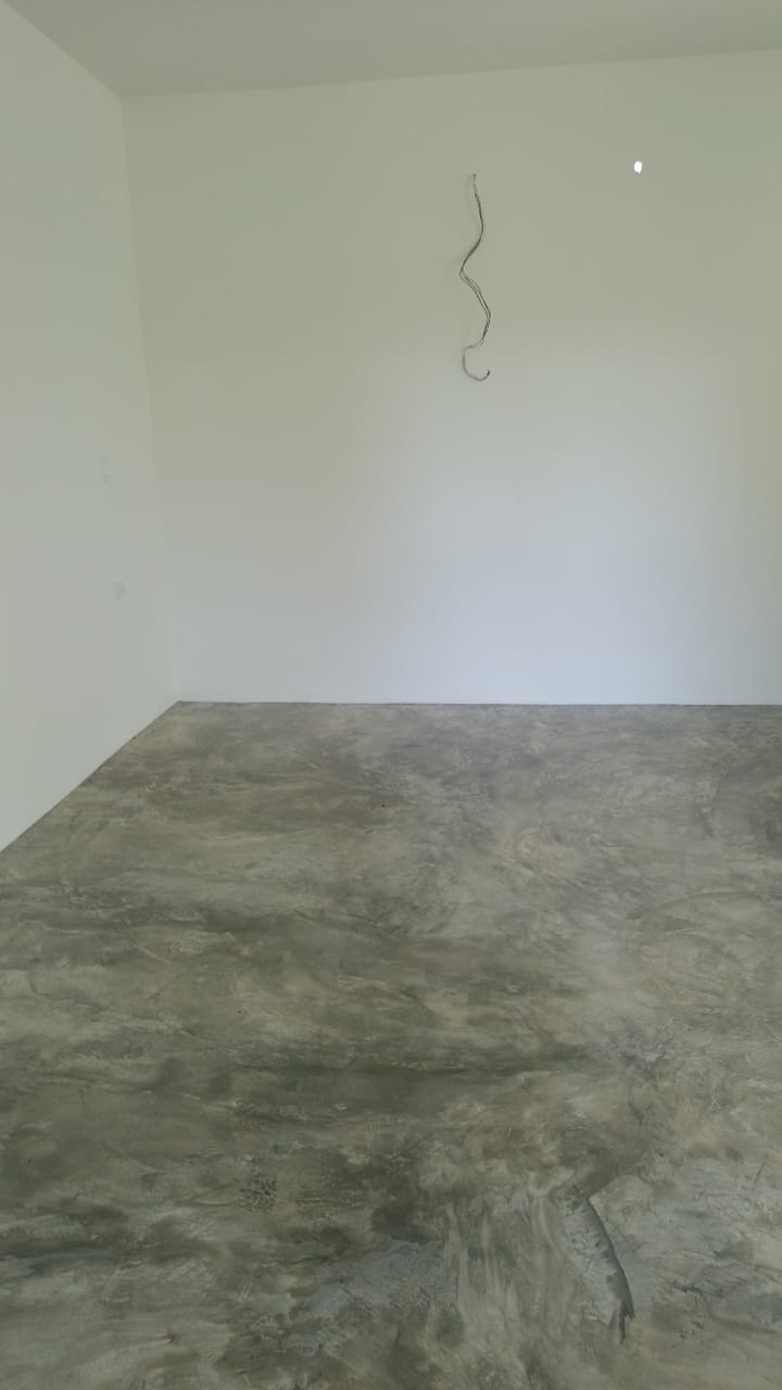 Una habitación vacía con paredes blancas y piso de cemento pulido.