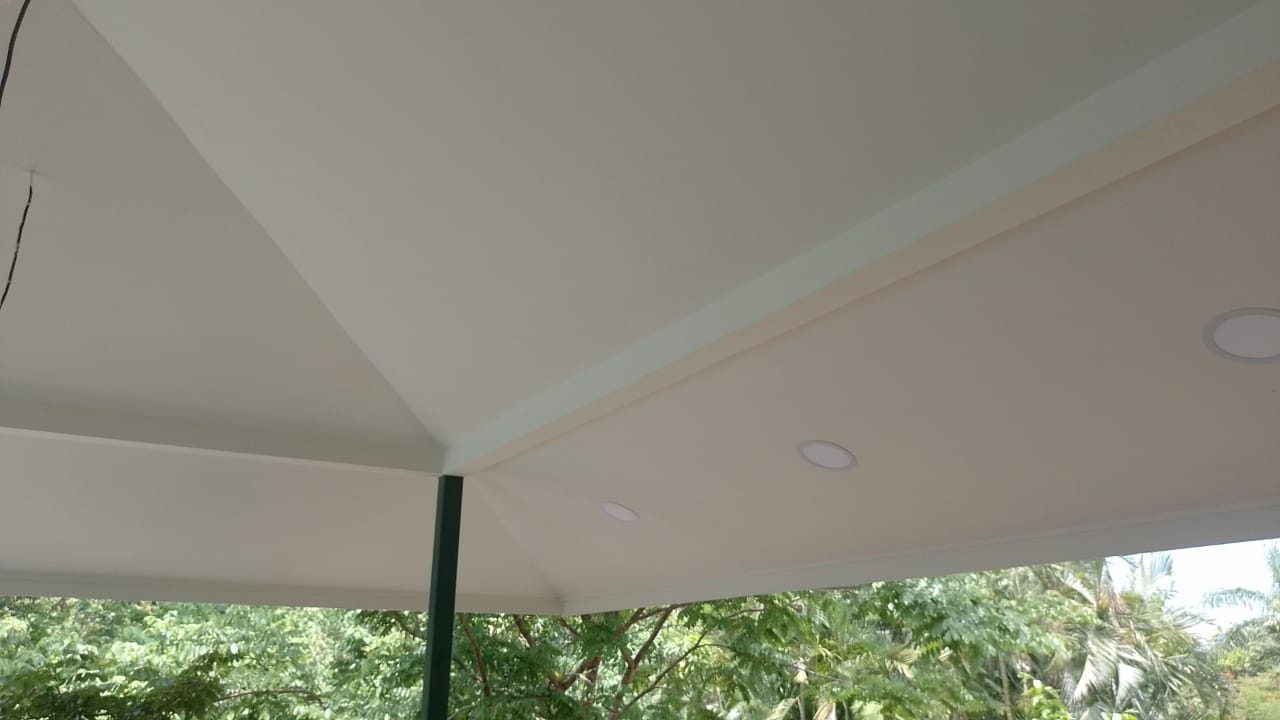 Se observa el techo interior de una estructura con iluminación empotrada y vista hacia árboles.