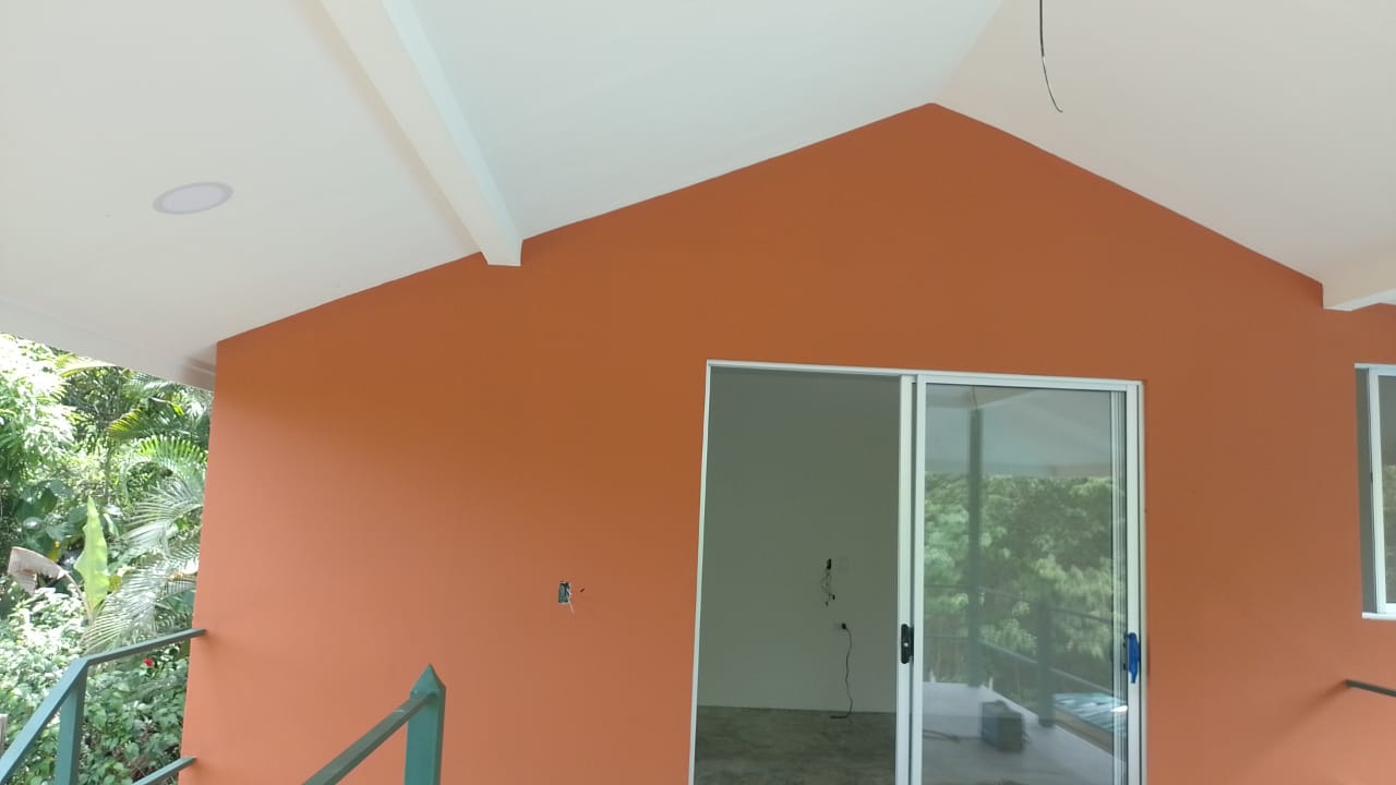 Una pared exterior recién pintada de color terracota con una puerta corrediza de vidrio.