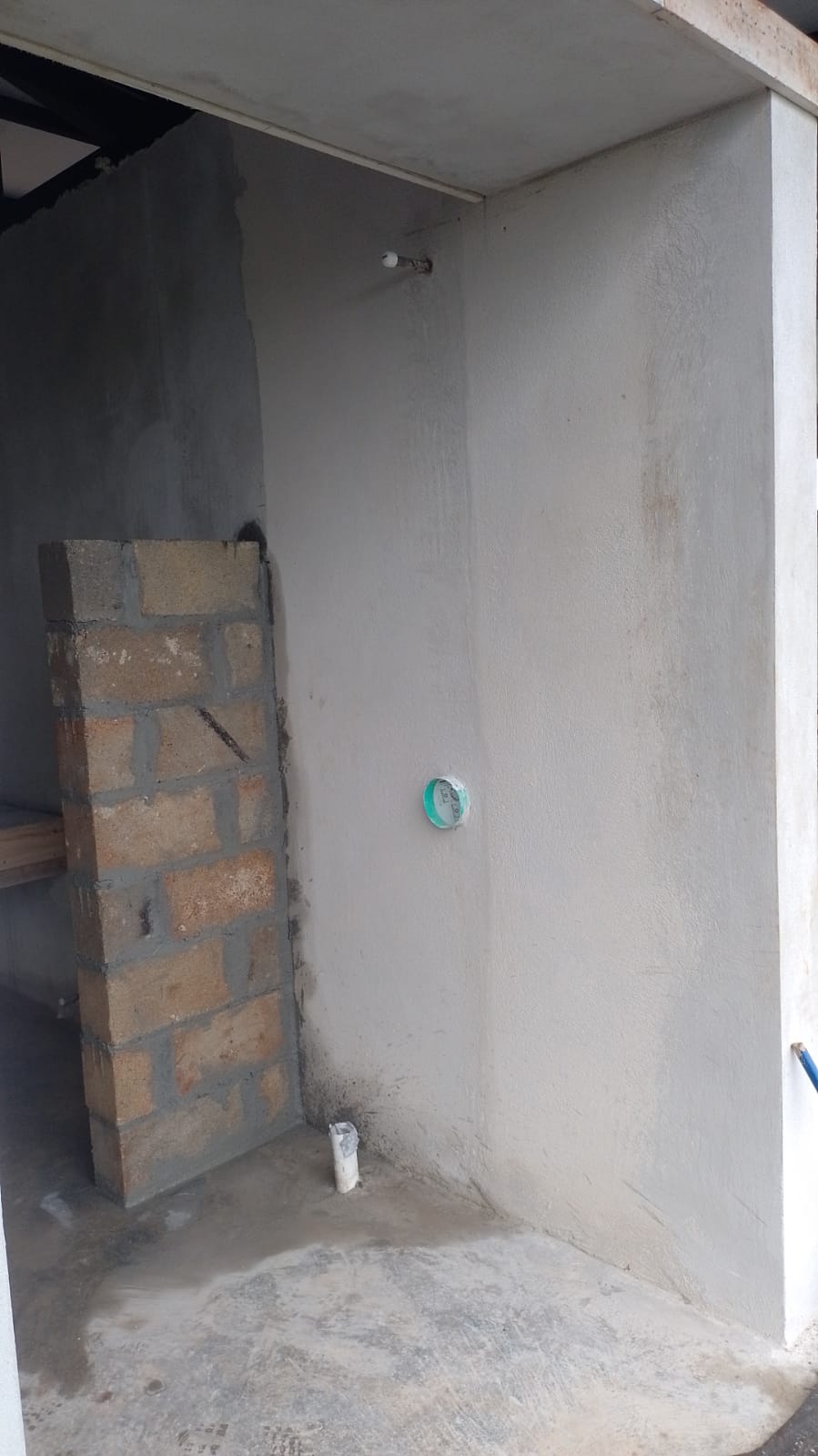 Se observa una pared en construcción con bloques de concreto y tuberías expuestas en una obra.